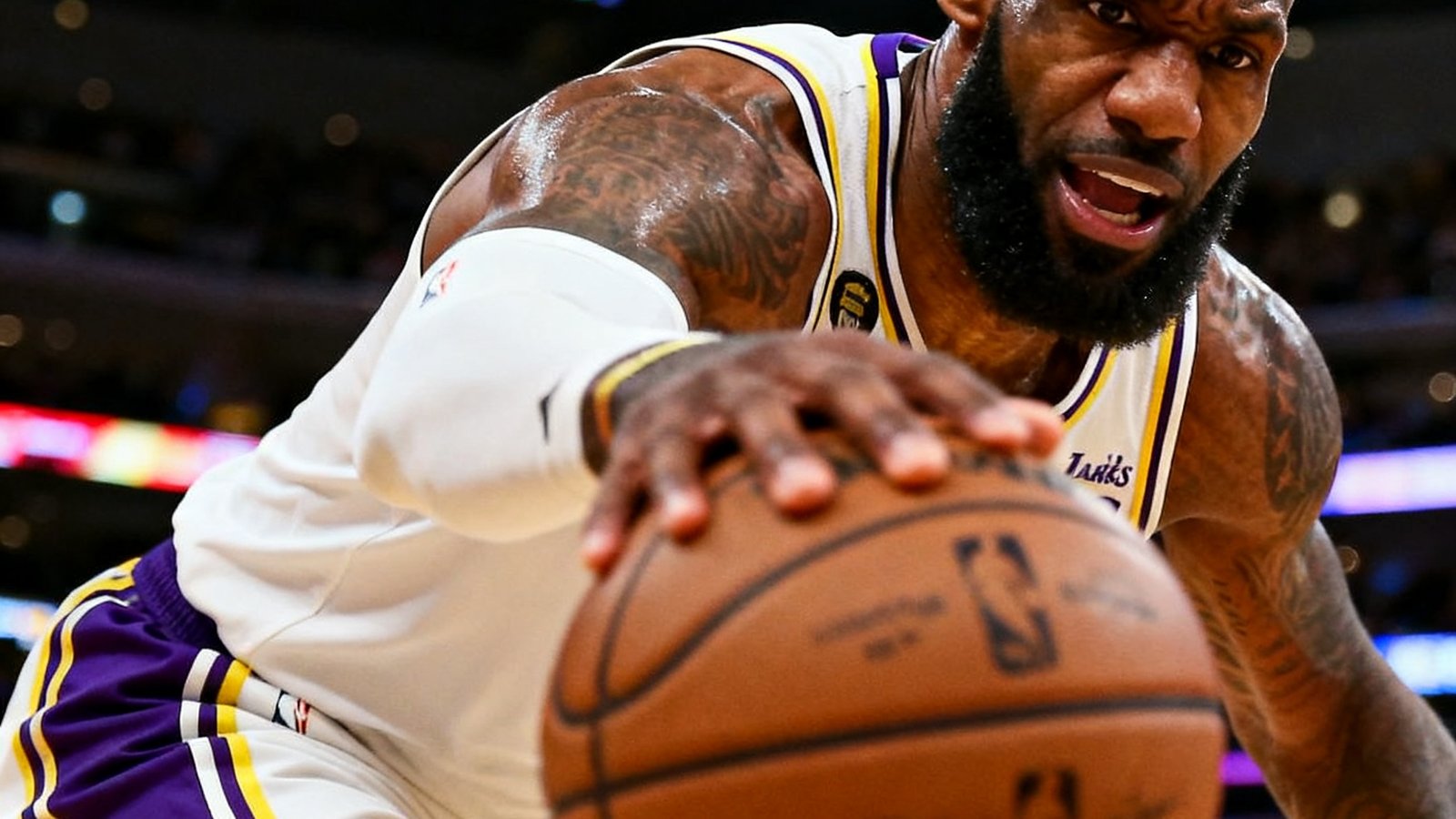 NBA赛场上湖人队詹姆斯突破上篮的特写画面，背景为记分牌和观众席